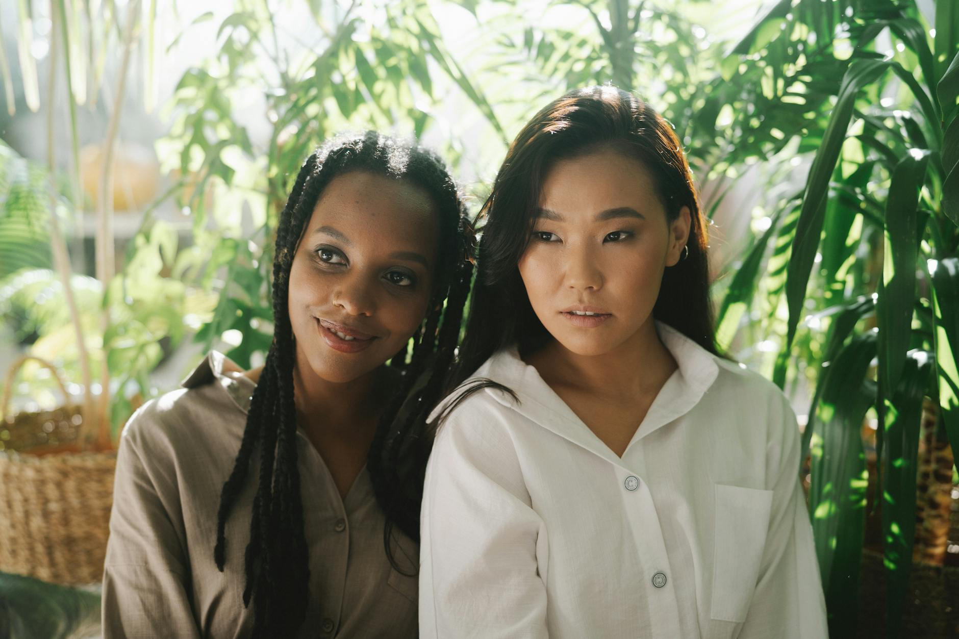 Two adults sitting together in calm, warm daylight among houseplants
