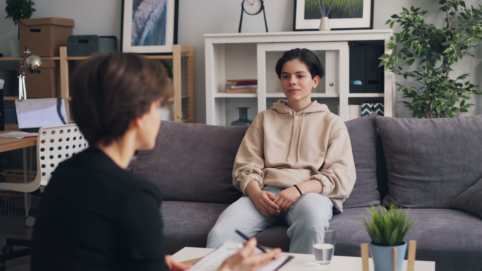 A young adult talking calmly with a therapist in a warm, private office