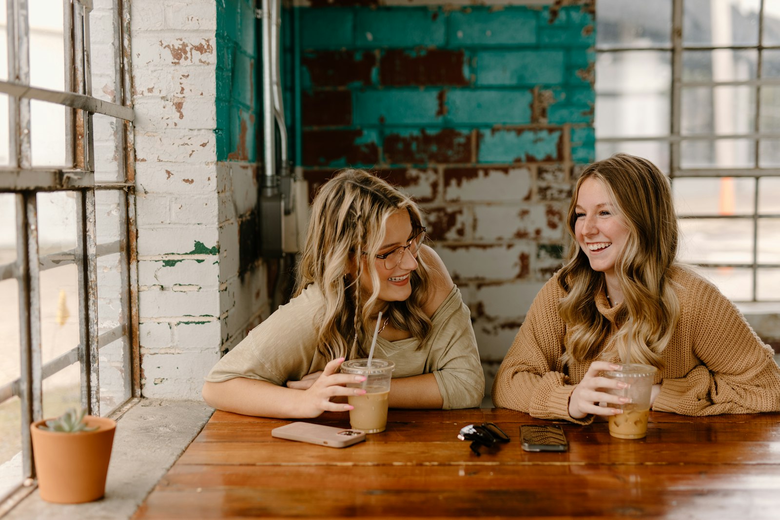 Two people talking warmly together over coffee in soft daylight